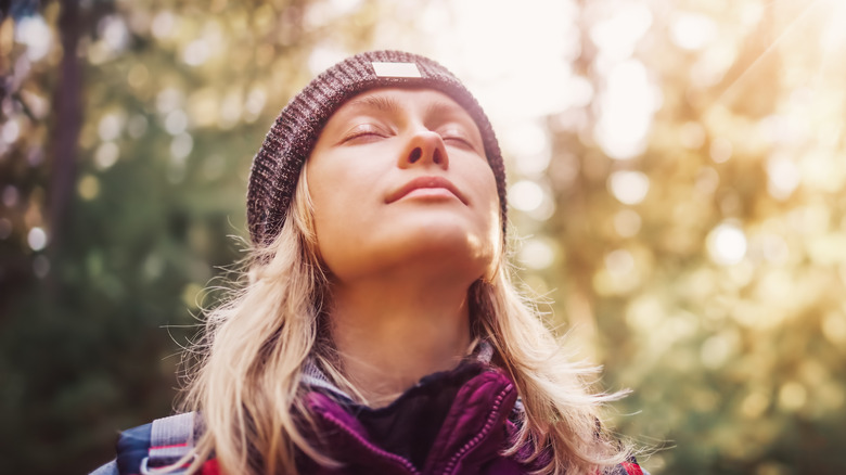 Woman in forest with face toward sun