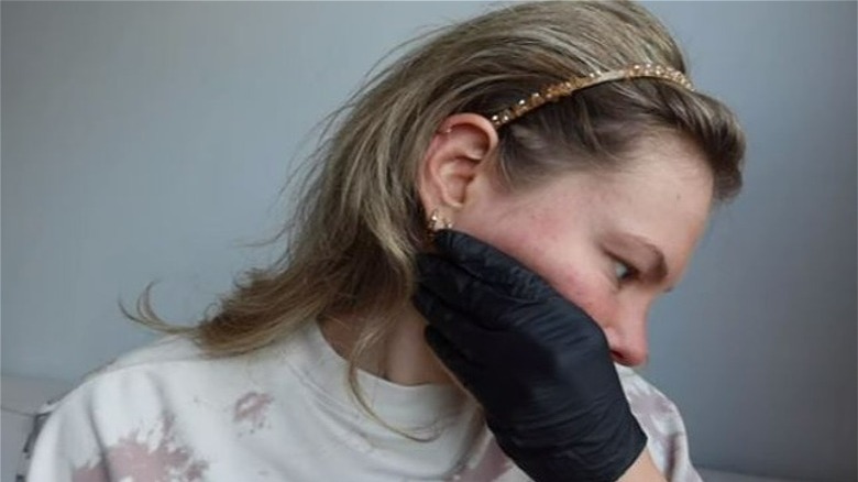 Woman with latex glove, thumb in mouth