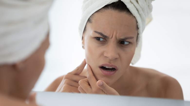 Woman looking in mirror upset