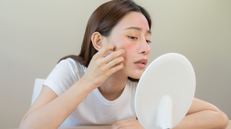 Woman inspecting her skin in mirror