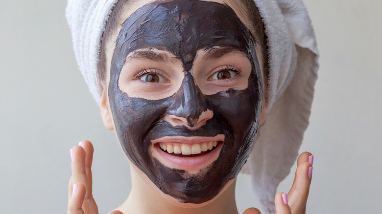 woman applying a charcoal mask on her face