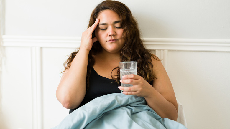 Woman with hangover drinking water