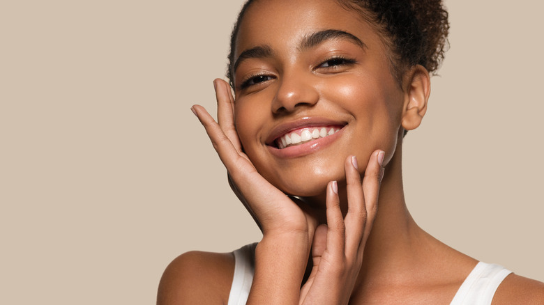 Woman smiling as she holds hands to her face