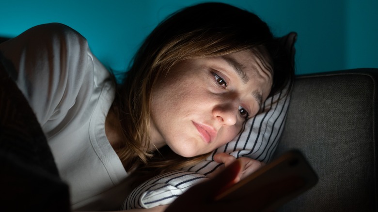 sad woman lying down with phone