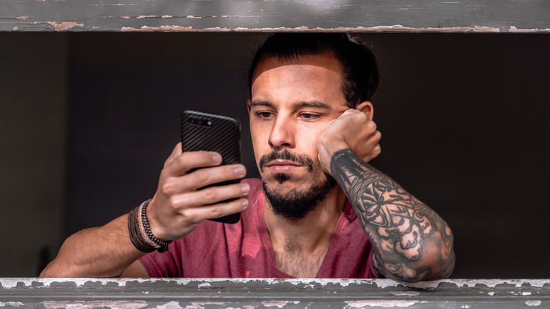 Bored Latino man using phone