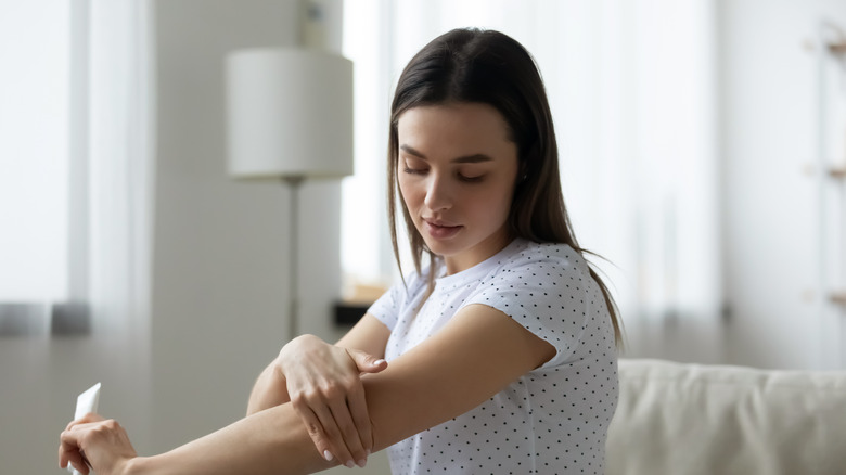 Woman applying cream to arm