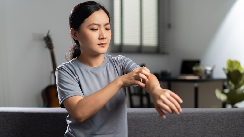 Woman scratching her left arm