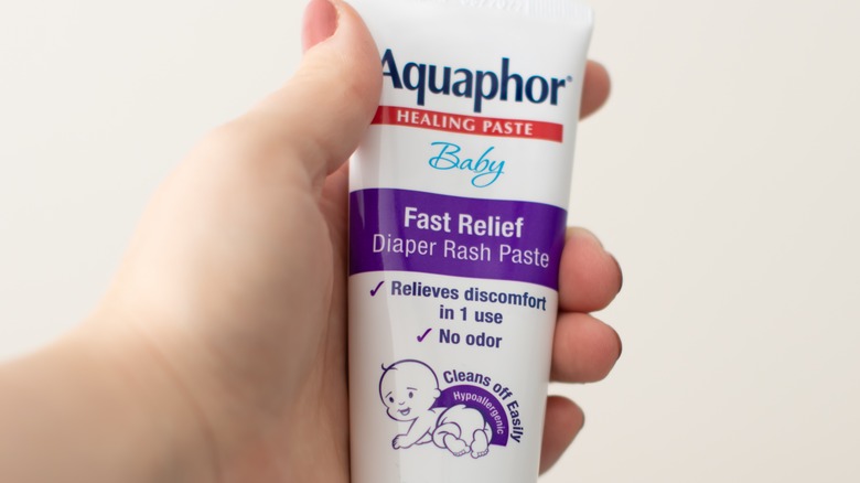 a hand holding Aquaphor tube