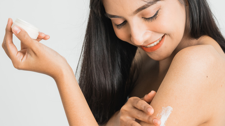 female applying moisturizer to body skin