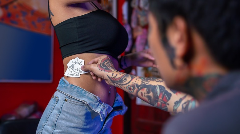 Tattoo artist applies sketch to woman's skin 