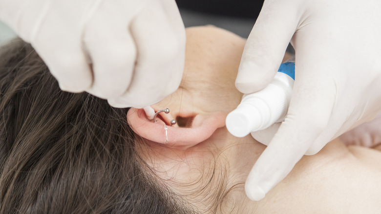 woman having ear piercing cleaned