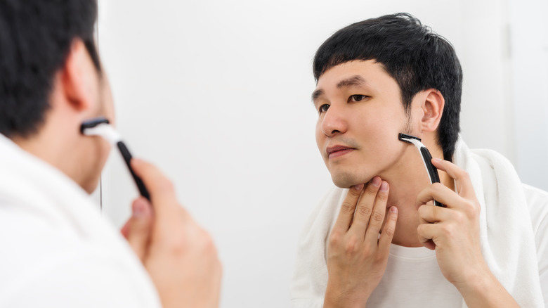 Asian man shaving his face