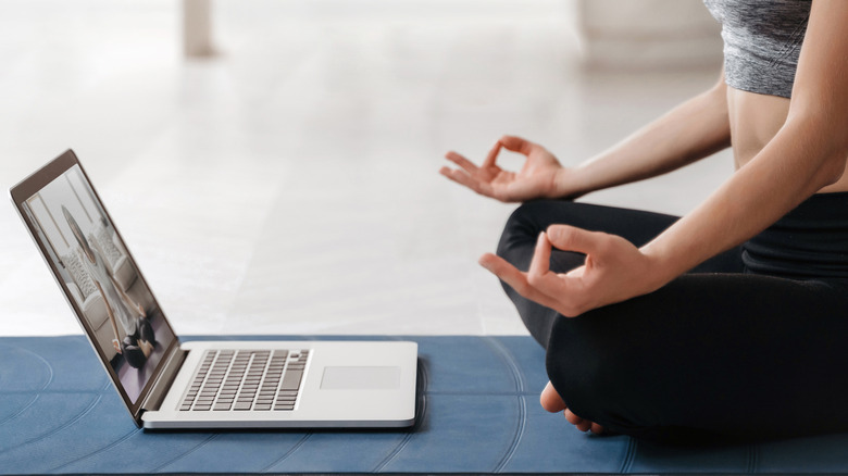 A woman doing yoga in front of a laptop