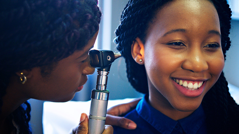 Woman having ear checked by doctor