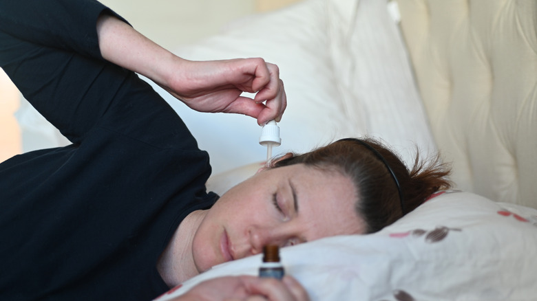 Woman using ear drops in bed