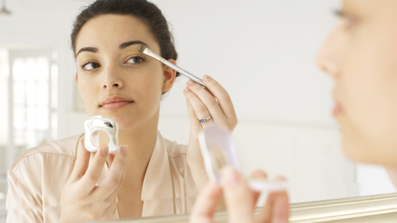 Woman doing her makeup in the mirror