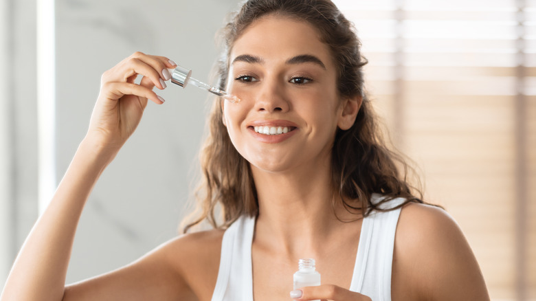 A woman applying face serum 