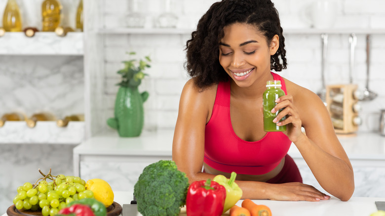 Woman drinking fresh-pressed juice near produce