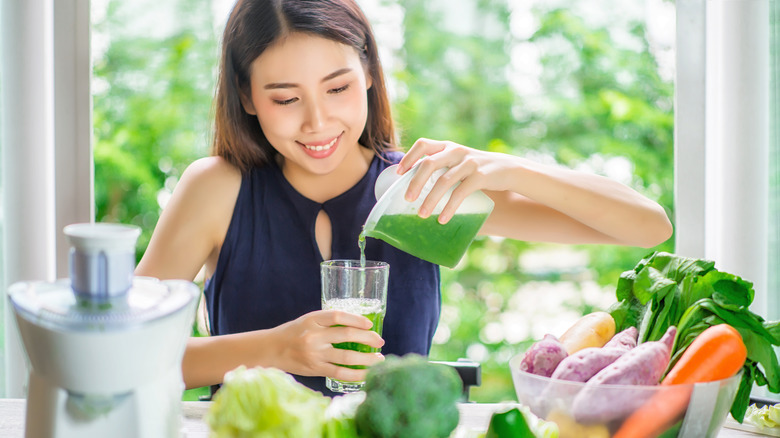 Woman pouring green juice into glass