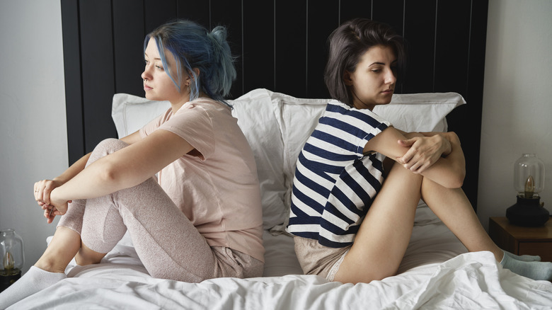 Two women sitting on bed