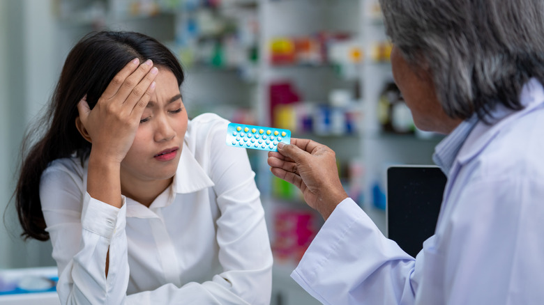 Women at pharmacy holds head in pain