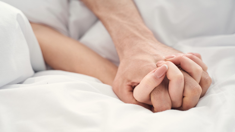 Couple holding hands in bed