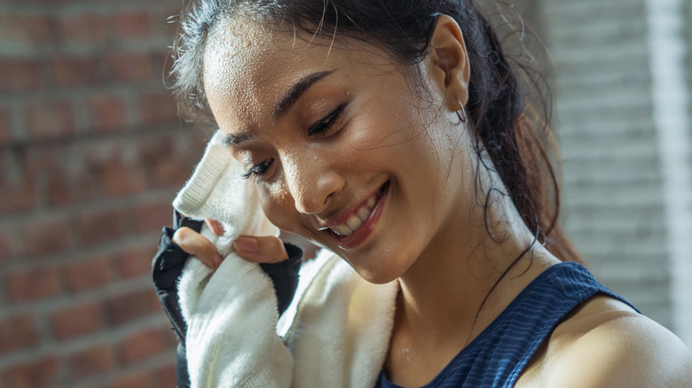 woman wiping sweat off her face with a towel