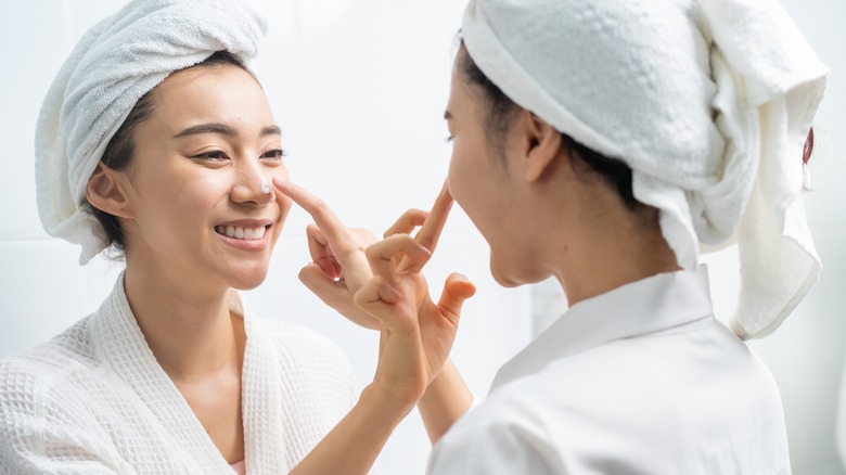 Asian women putting moisturizer on each other