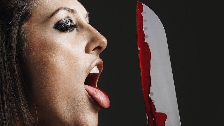 woman licking bloody knife