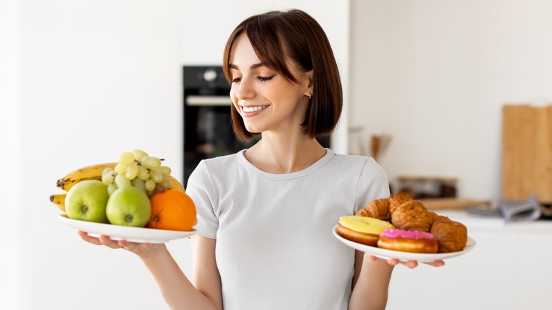 Woman evaluating two plates of food in kitchen