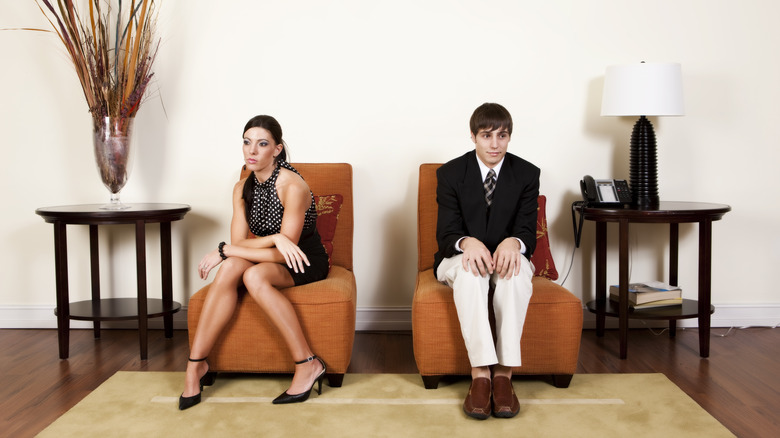 Awkward couple sitting on chairs 