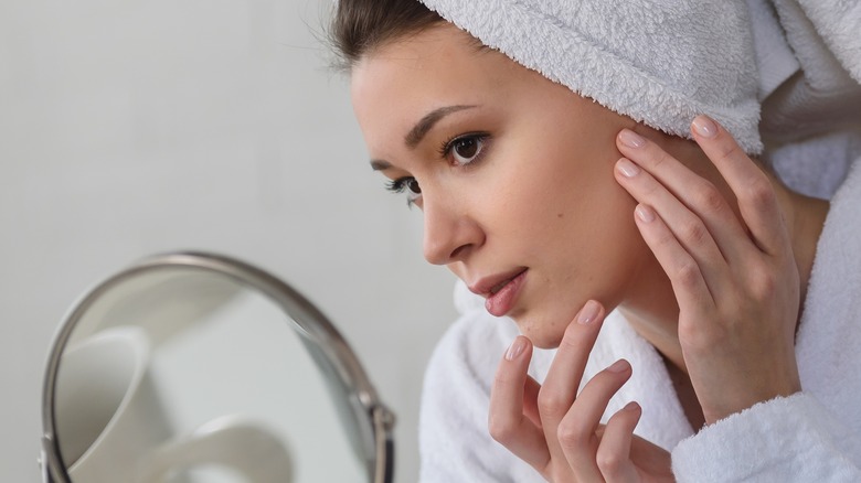 woman checking acne in mirror