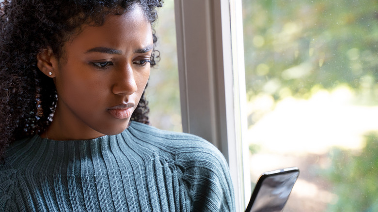 woman looking at phone confused