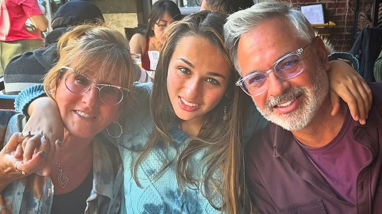 Jazz Jennings wrapping her arms around her parents at a restaurant.