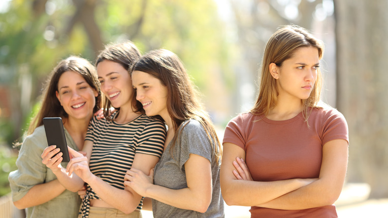 Woman left out from group of friends taking selfie