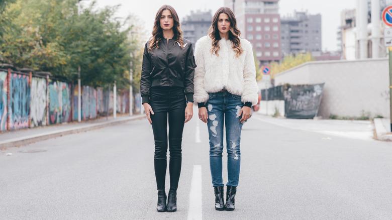 One women in dated skinny black jeans and another in straight-leg ripped jeans