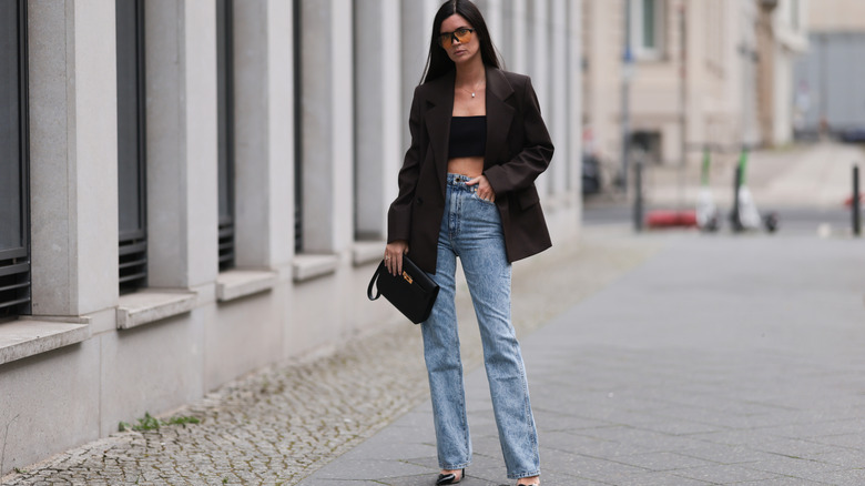 Woman wearing high-waisted jeans and a black blazer over a crop top