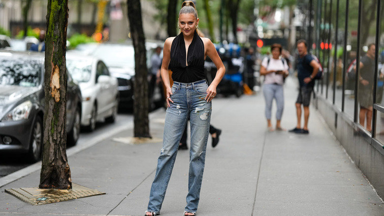 A woman wearing faded, ripped jeans with frayed bottoms