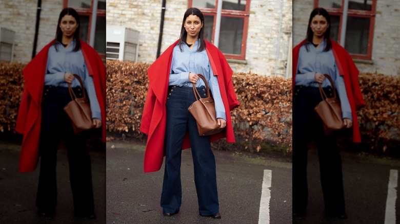 A woman wearing high-waisted jeans with a red coat draped over her shoulders