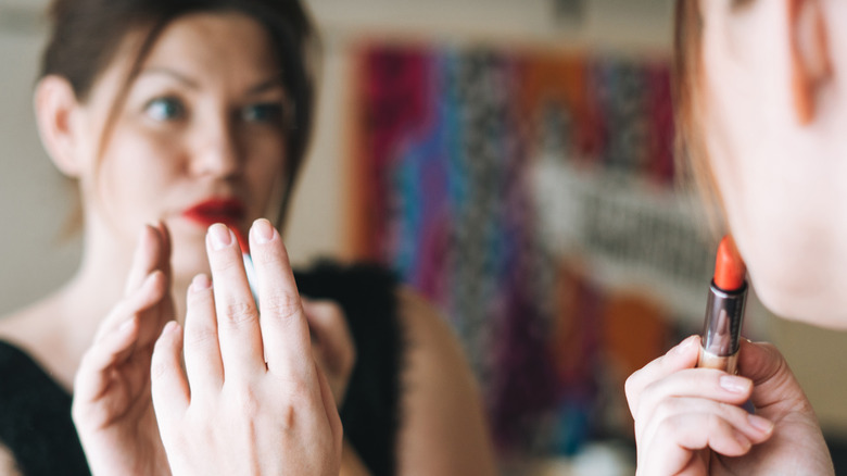 woman putting on lipstick