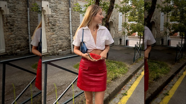 Girl wearing scarlet leather skirt and holding watermelon slice