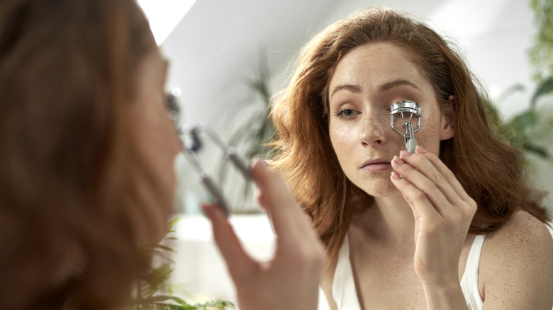 woman using eyelash curler