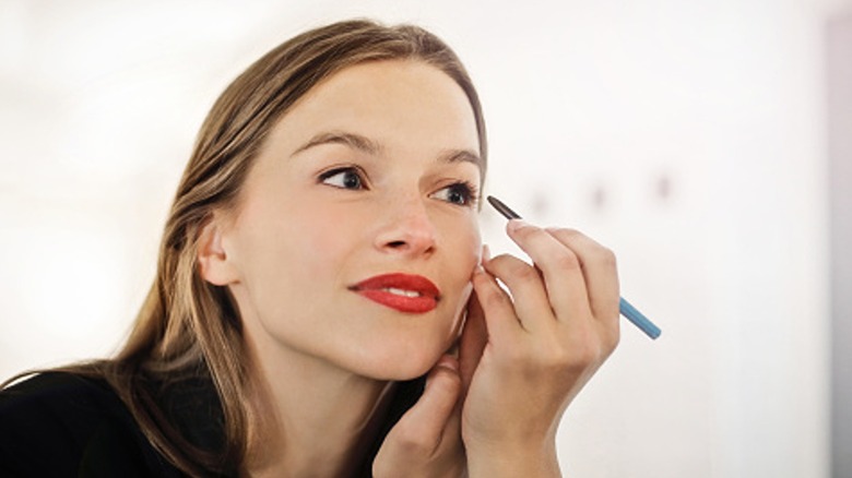 Woman putting on pencil eyeliner