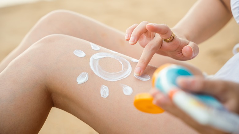 woman applying sunscreen on legs