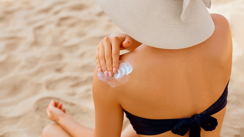 woman applying cream on shoulder