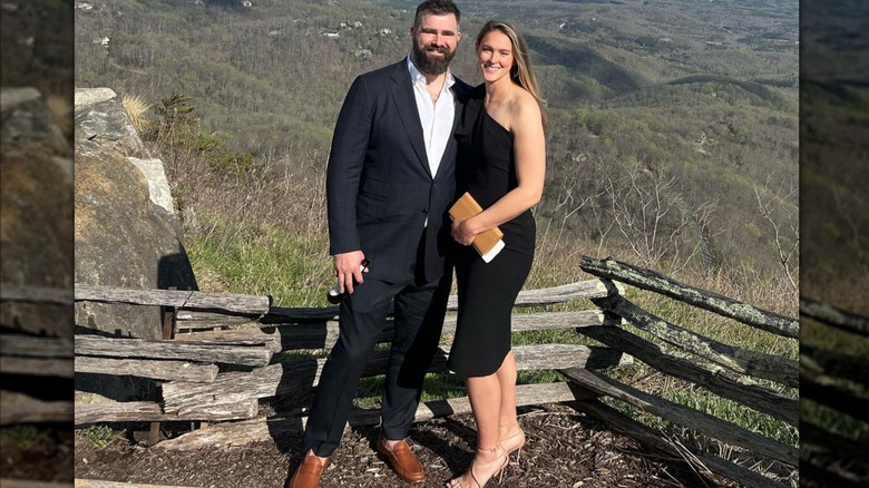 Jason and Kylie Kelce, in a black dress, standing on a mountainside