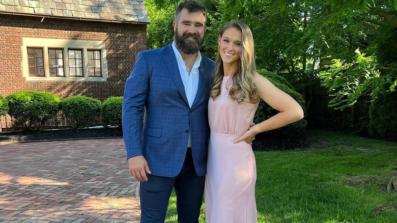 Jason and Kylie Kelce, in a pink dress, posing at a wedding