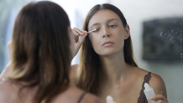 Woman applying product to eye area with Q-tip