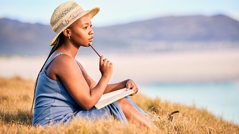 Woman writes in journal in meadow