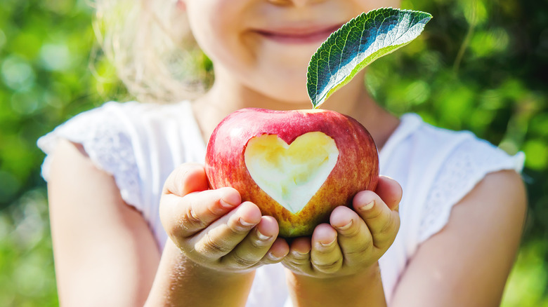 Child holding apple with heart